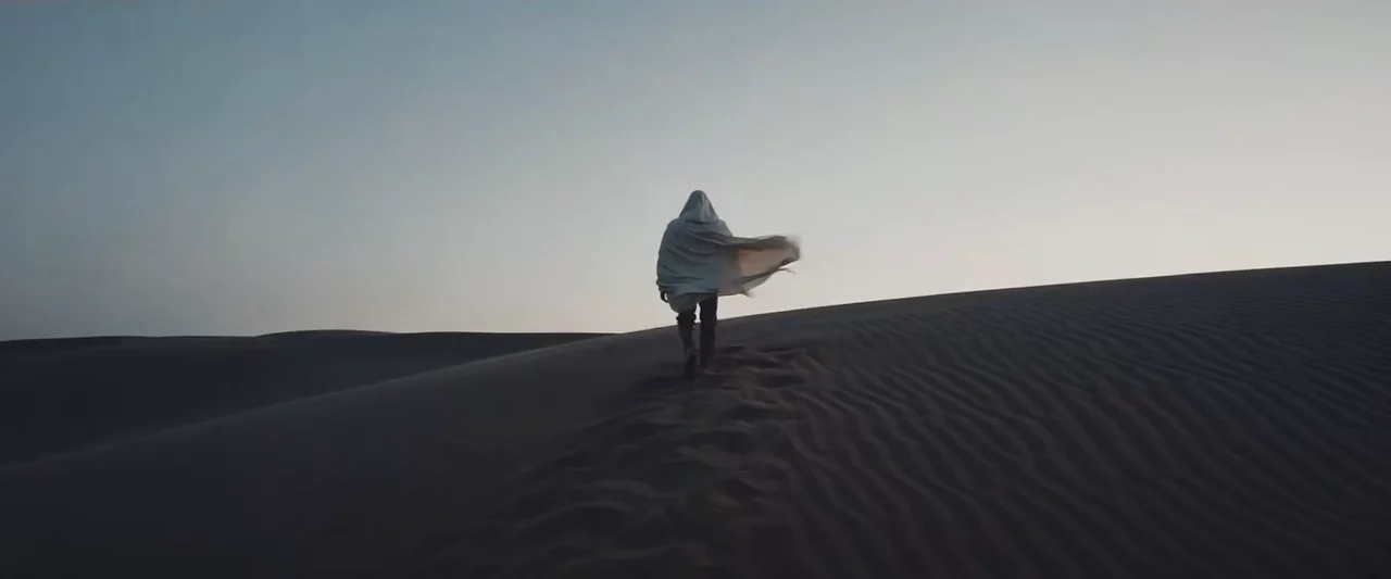 A cloaked figure crosses a dune in Runway’s Gen-4 launch imagery